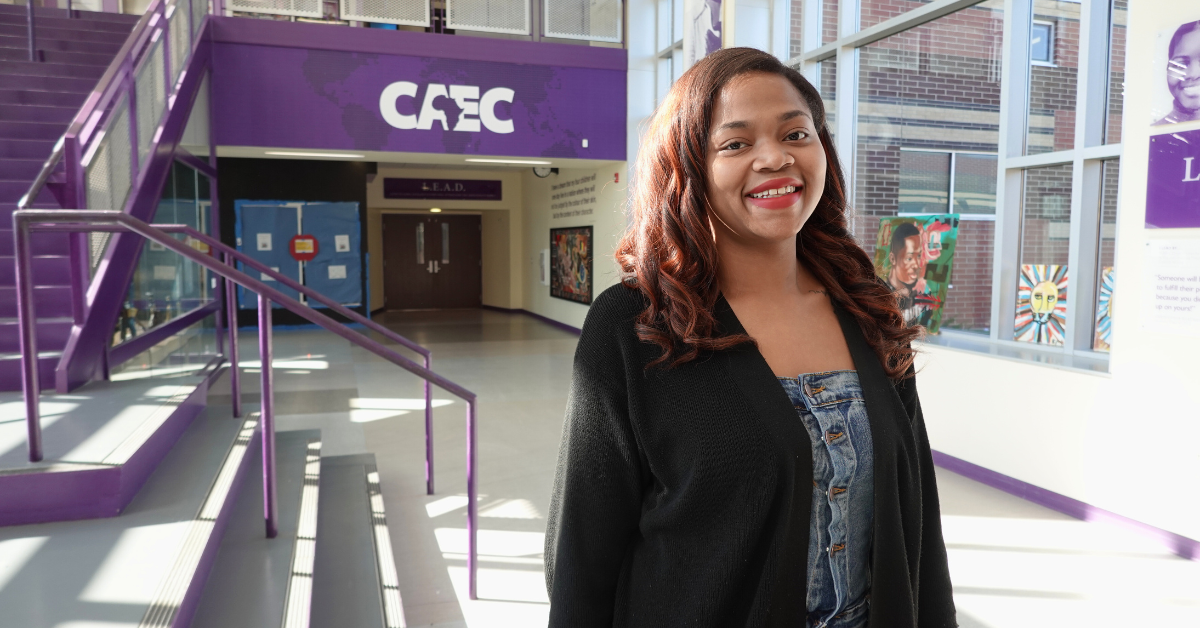 teacher in front of stairs and sign